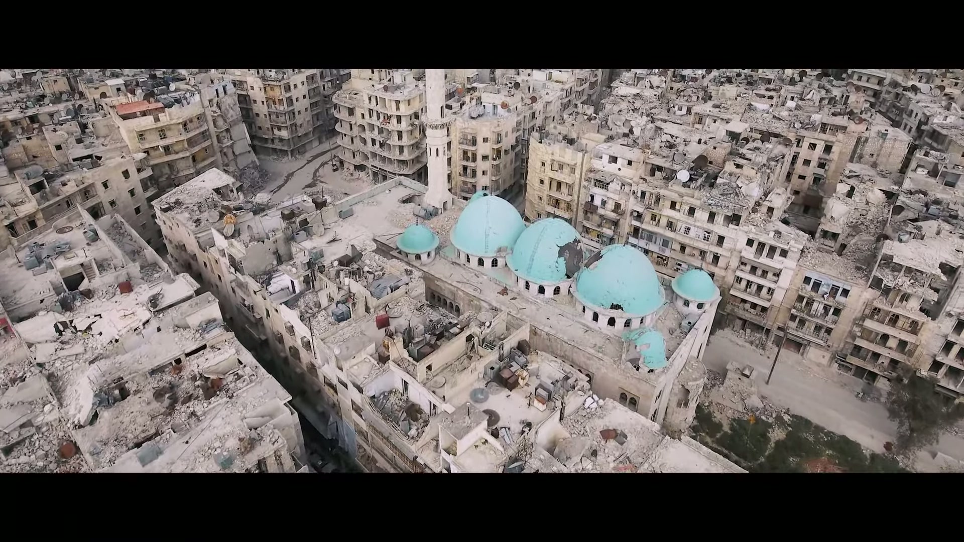 Aerial view of a destroyed city with a domed mosque