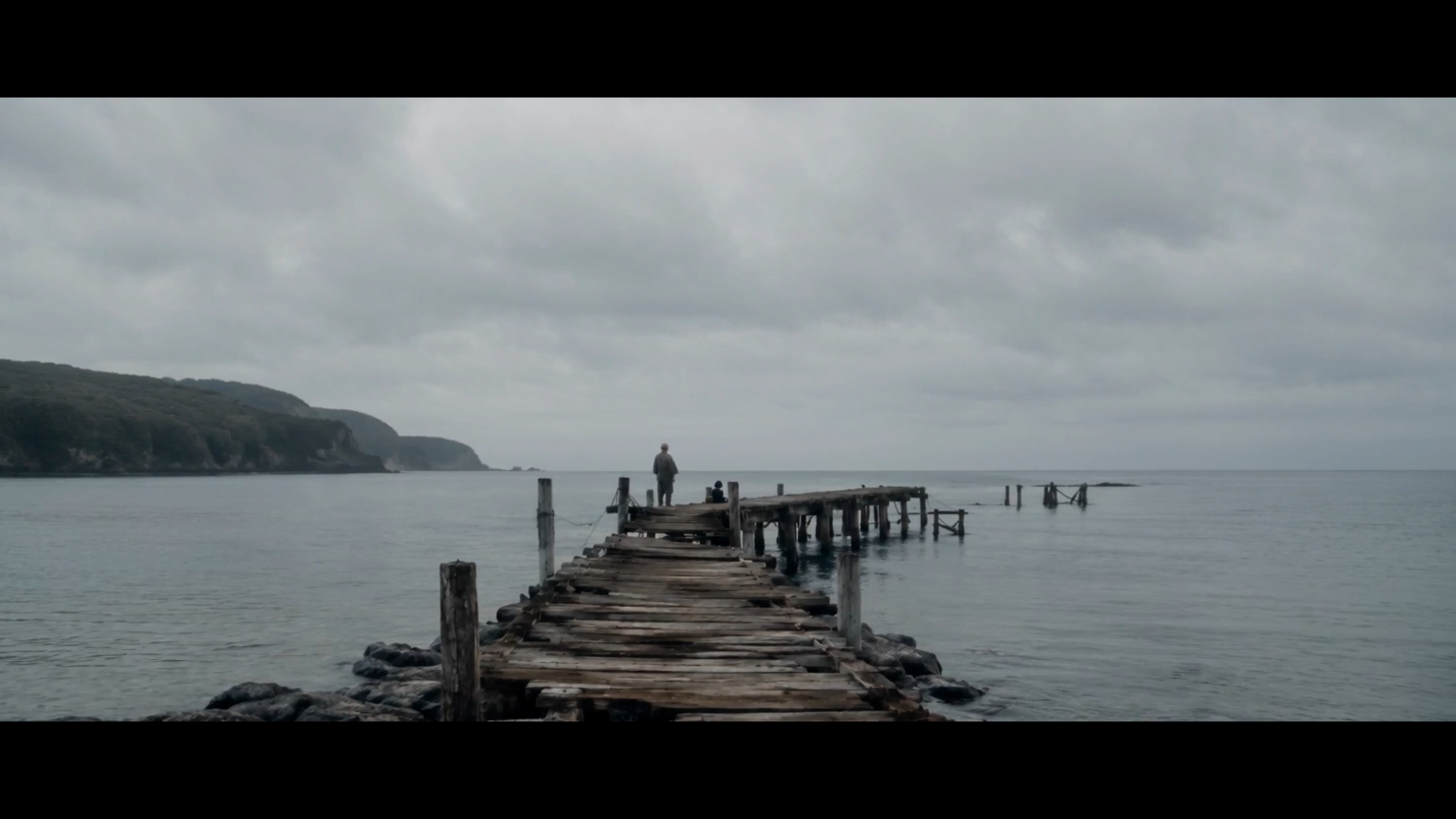 A lone figure at the end of the pier under an overcast sky